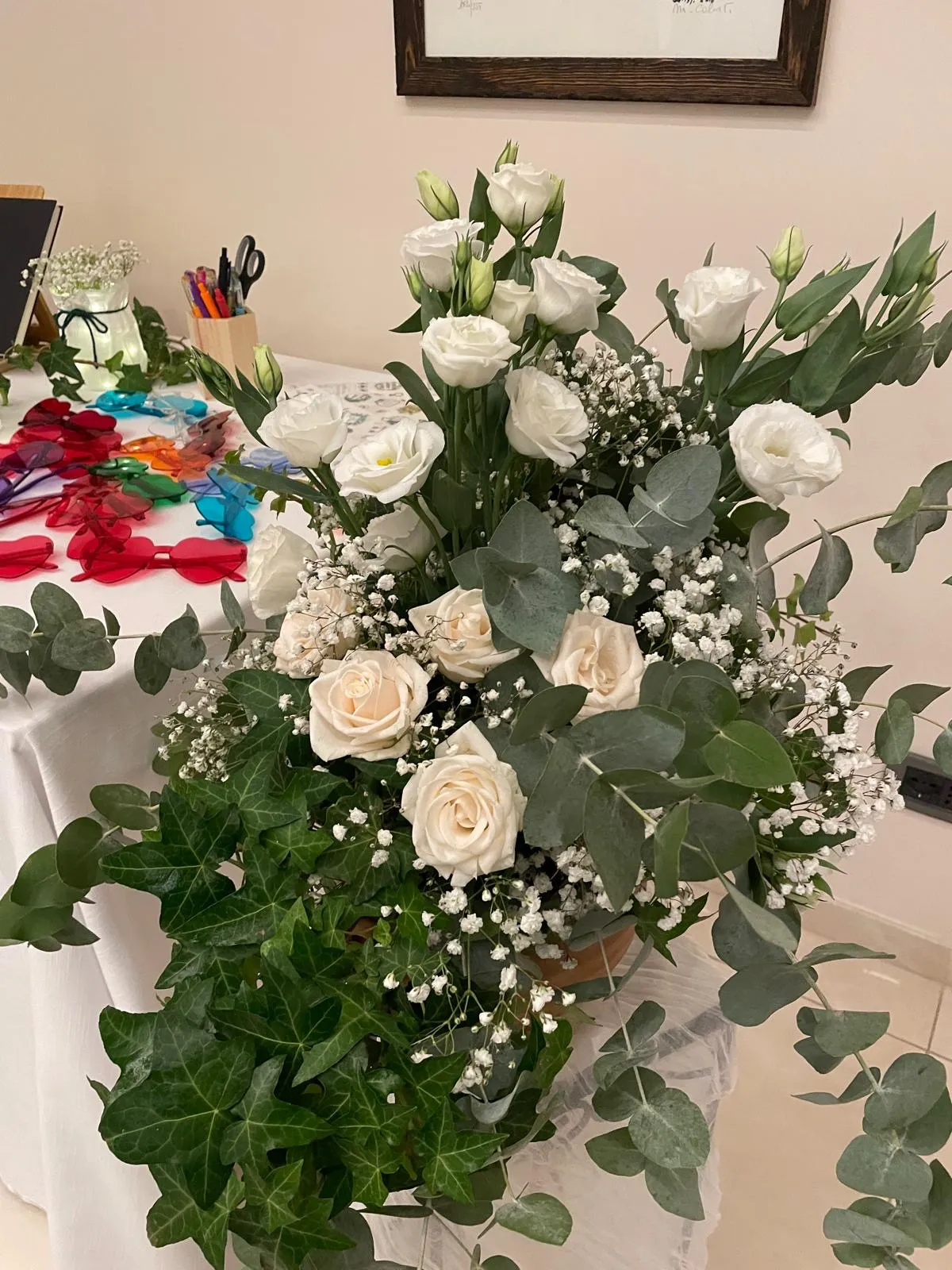 Composizione floreale con rose avorio, lisianthus ed eucalyptus su tavolo di preparazione