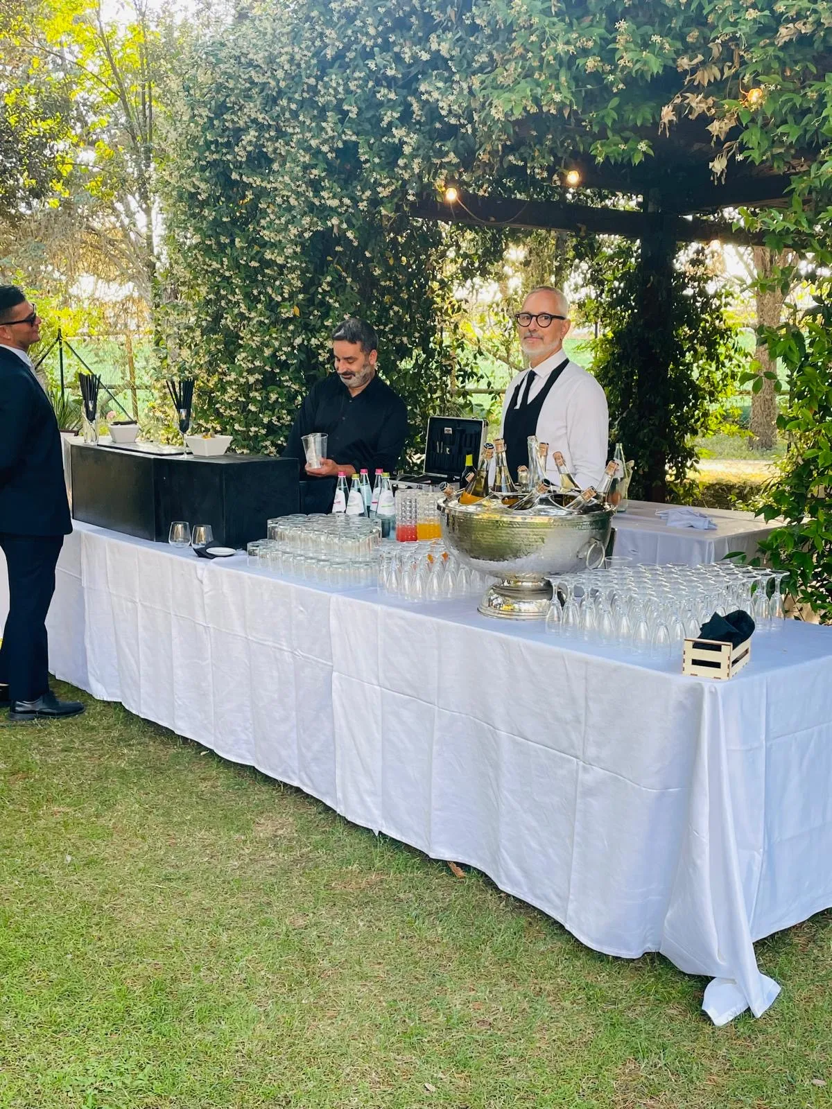 Bancone bar allestito all'aperto con barman e staff durante un ricevimento