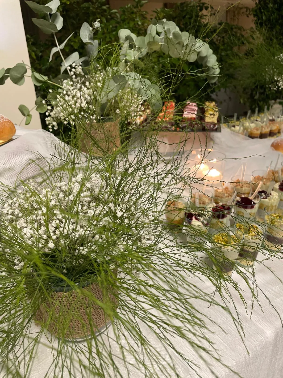 Centrotavola verde con gypsofila ed eucalyptus su tavolo buffet dolci