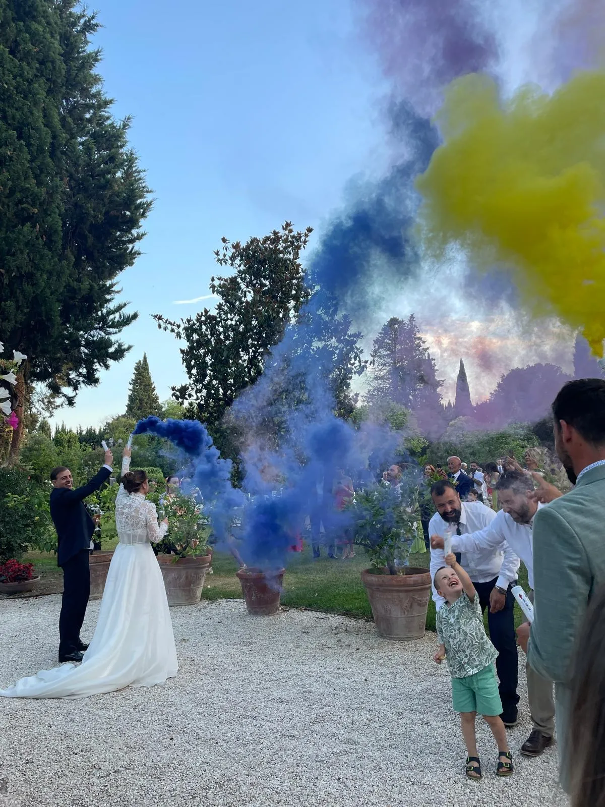Sposi e ospiti che lanciano fumogeni colorati durante festeggiamento all'aperto