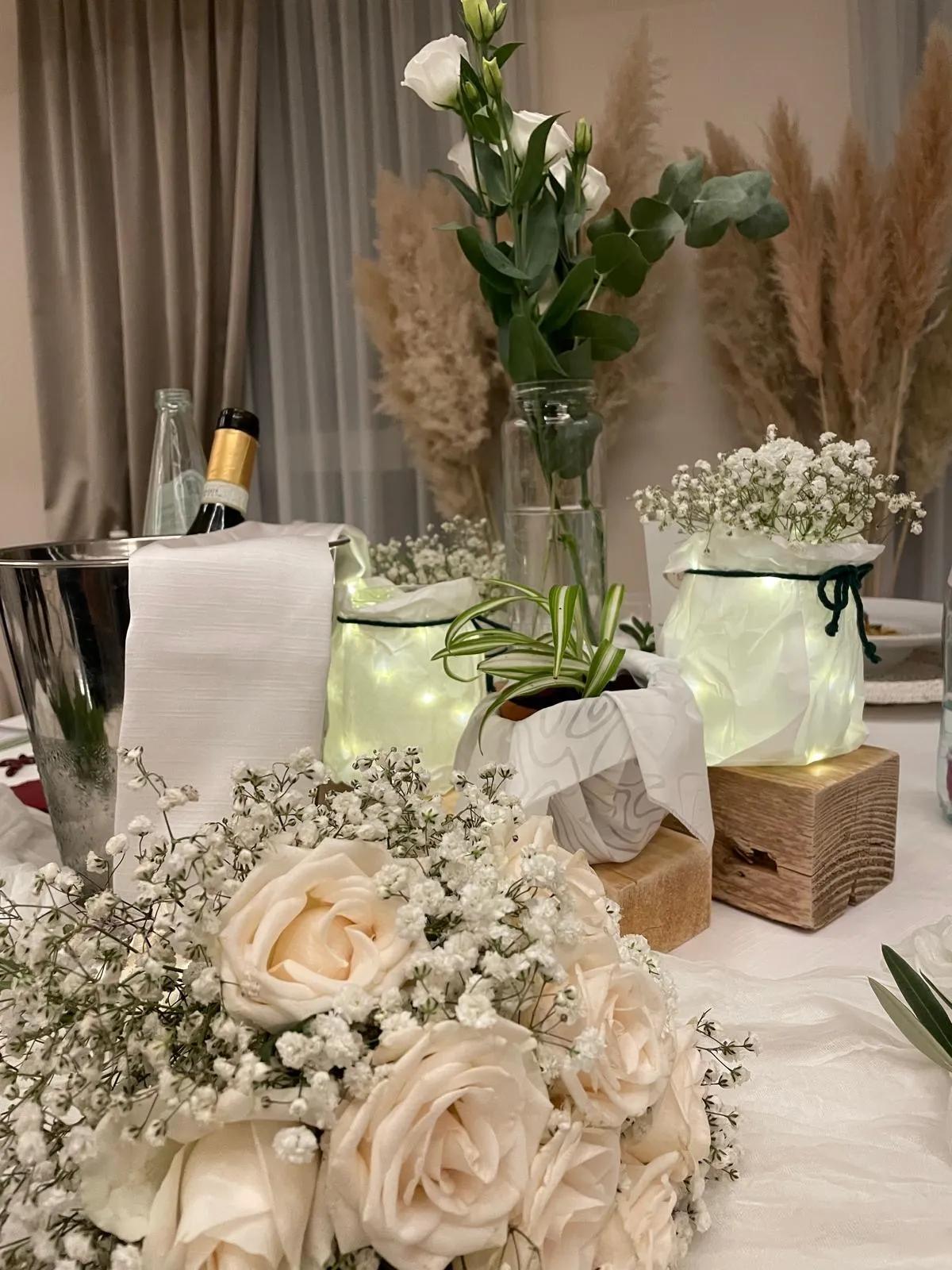 Tavolo allestito con bouquet di rose avorio, gypsofila e lanterne luminose