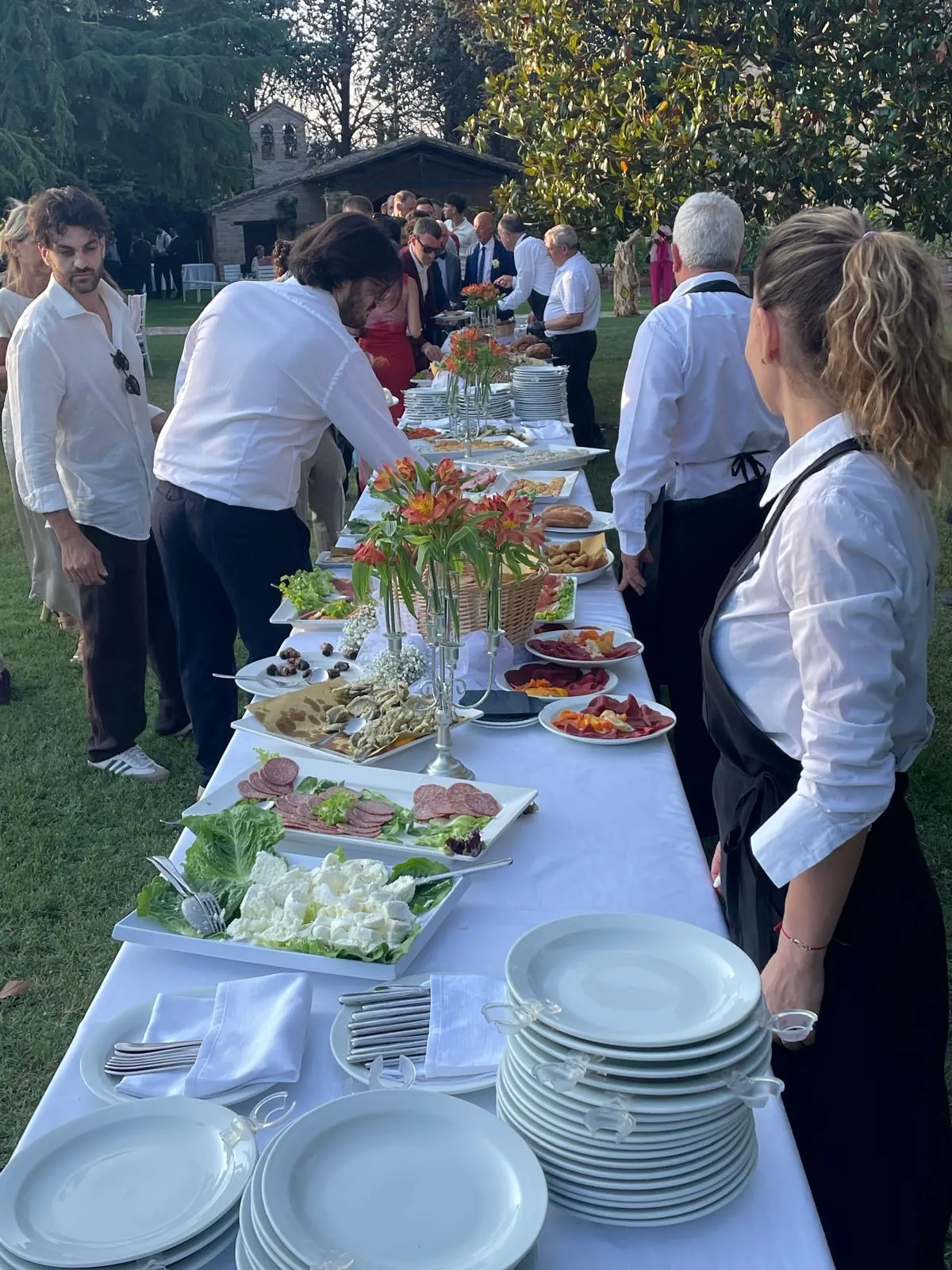 Buffet all'aperto con ospiti in fila e staff al servizio