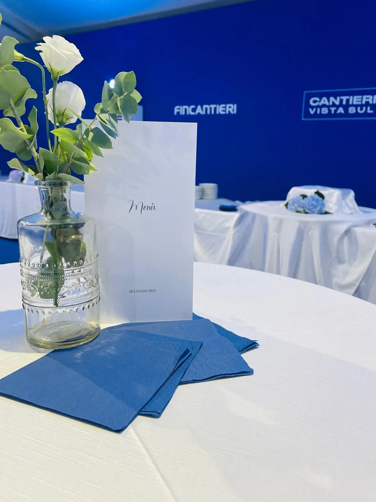 Centrotavola con fiore bianco e menu su tovagliolo blu