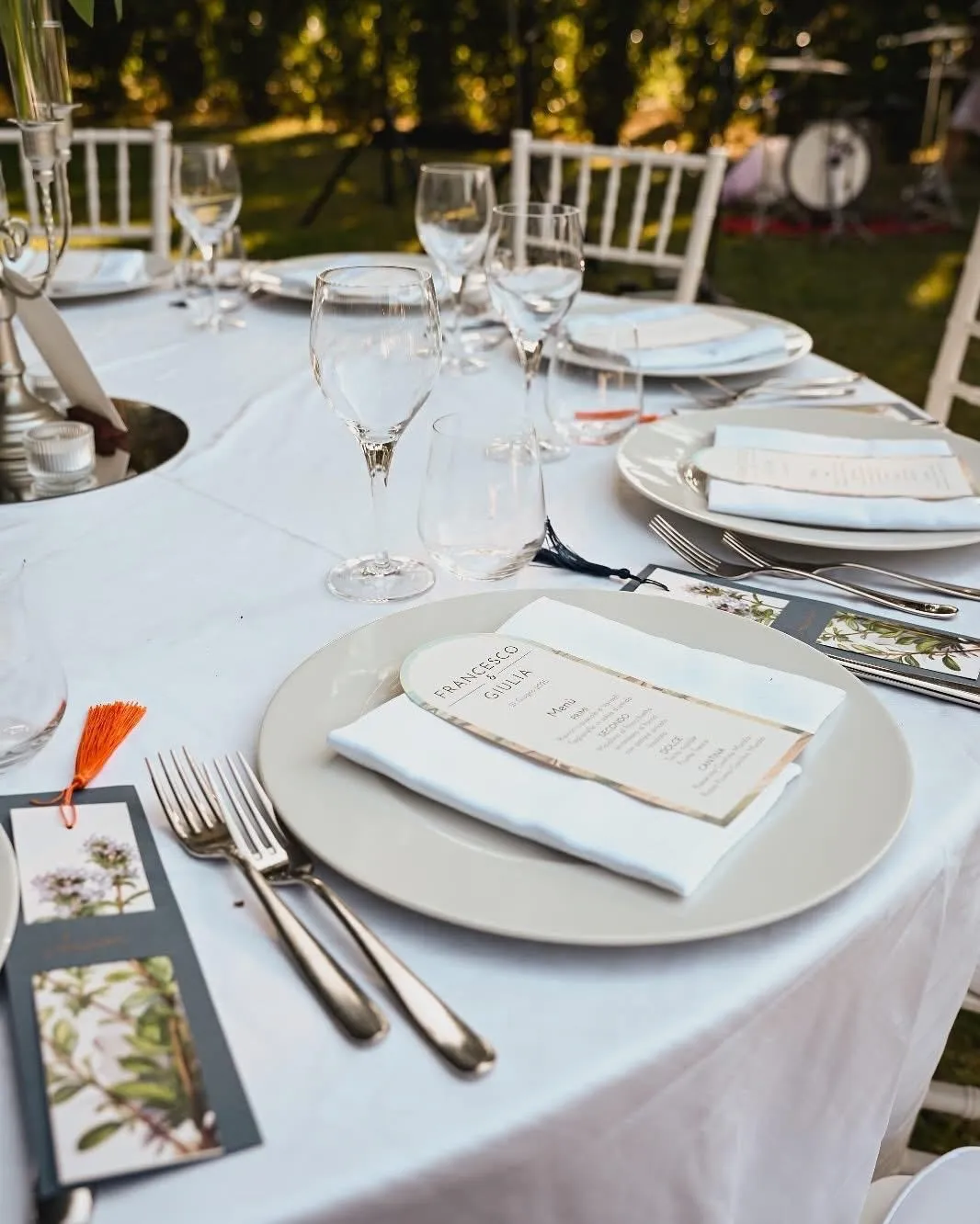 Dettaglio posto tavola con piatto, menu personalizzato e bicchieri apparecchiati per ricevimento