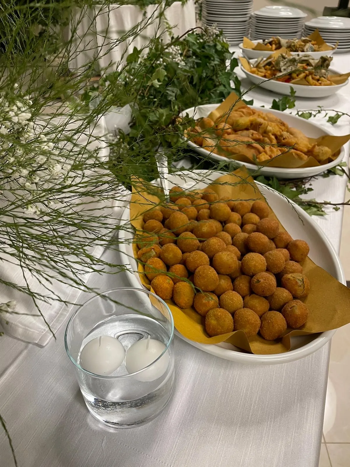 Vassoi di fritti misti e finger food caldi su tavolo buffet con tovaglia bianca