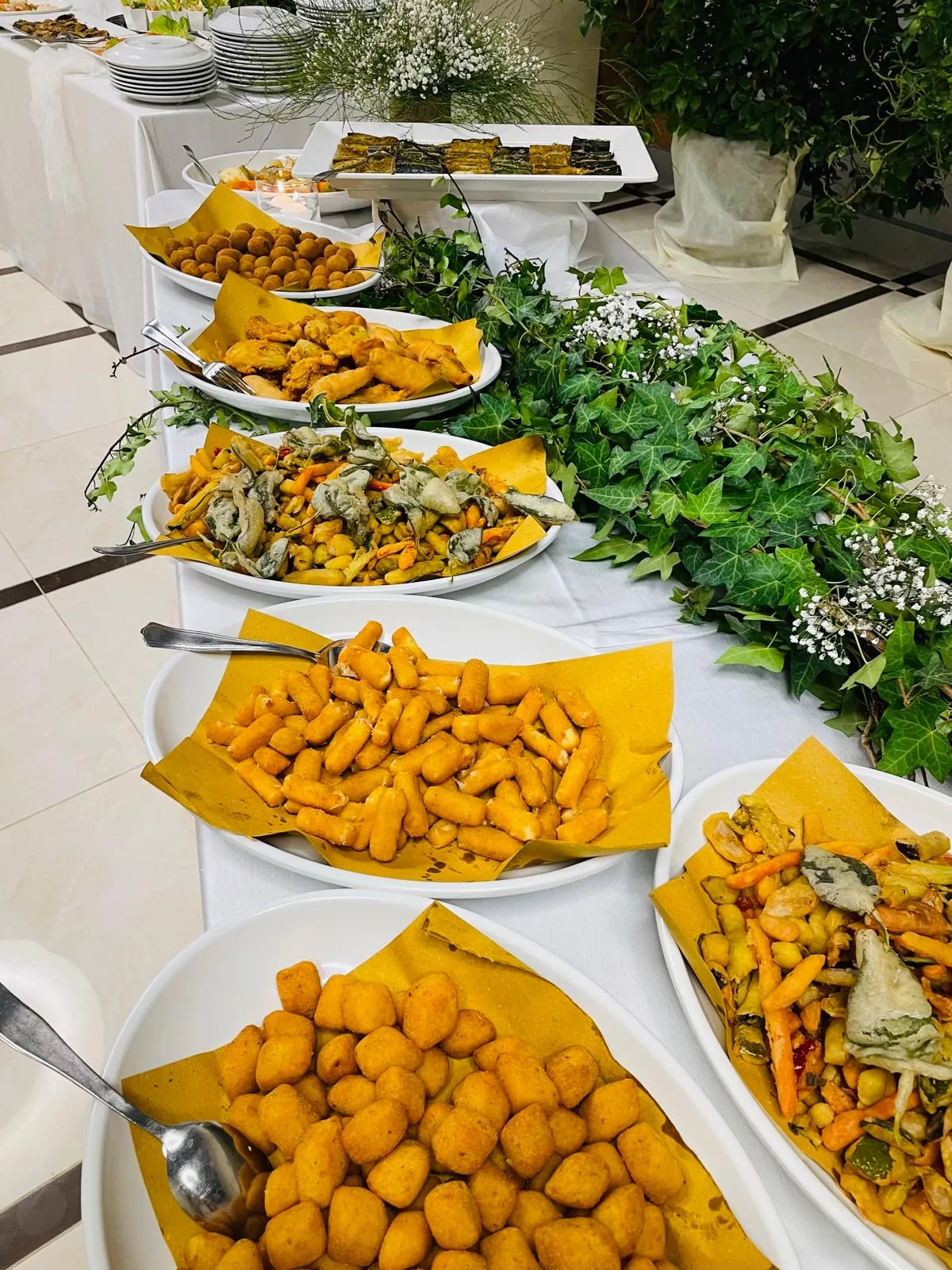 Buffet caldo con vassoi di fritti, verdure e finger food per catering eventi