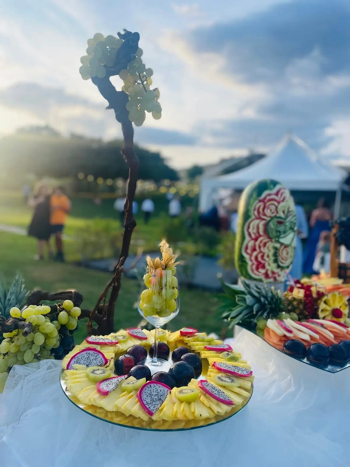 Buffet di frutta scenografico all'aperto con ananas, uva e pitaya