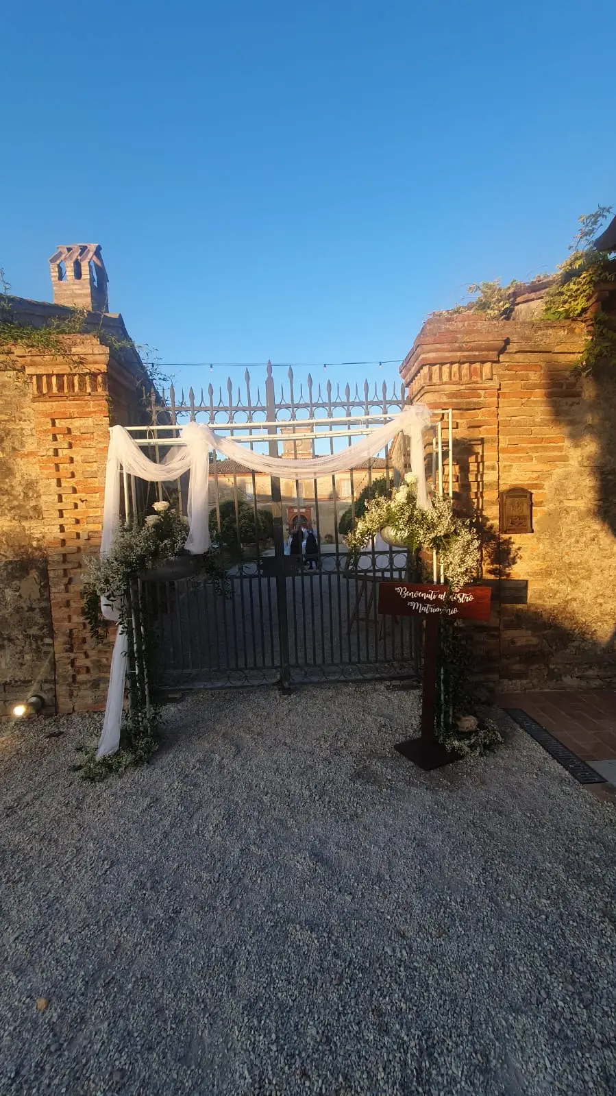 Ingresso della villa con cancello in ferro decorato da teli bianchi e fiori