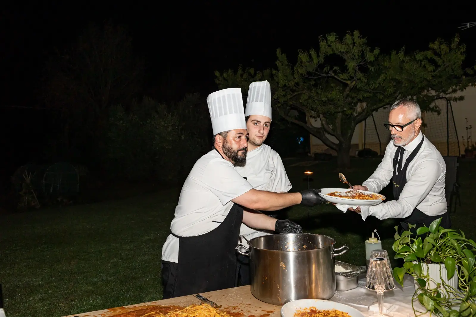 Chef che impiattano la pasta mentre il cameriere prende il vassoio per il servizio