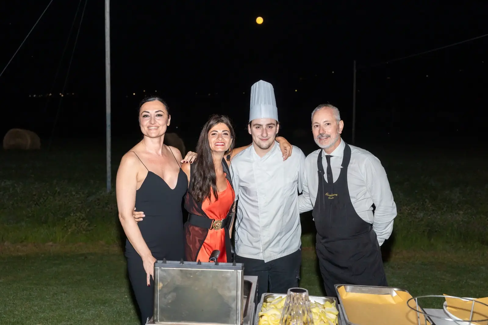 Due ospiti e due membri dello staff in posa sorridente davanti alla postazione di servizio serale