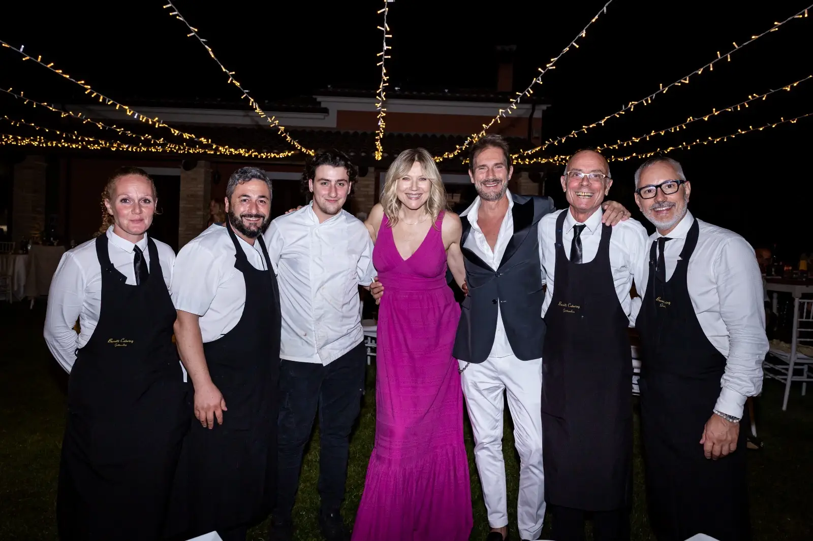 Gruppo di staff e ospiti sotto fili di luci serali