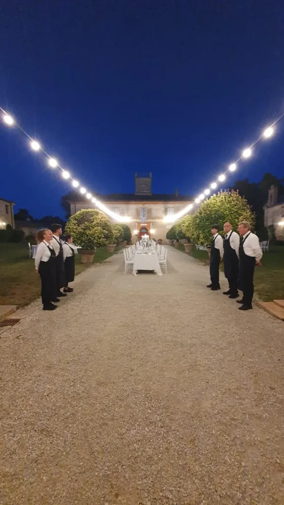 Viale illuminato da fili di luci di sera con i camerieri in fila