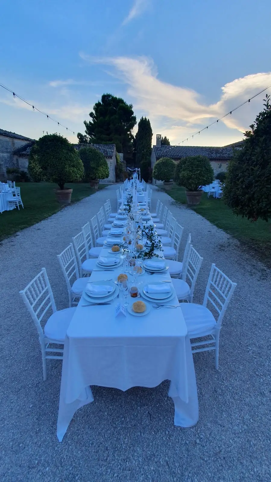 Vista panoramica corte con tavolo imperiale siepi e cielo al tramonto