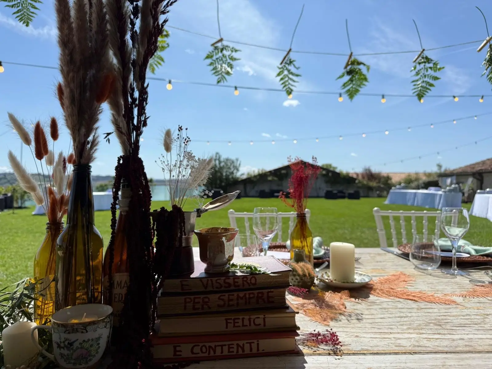 Tableau country con libri vintage candele bottiglie e pampas su tavolo legno