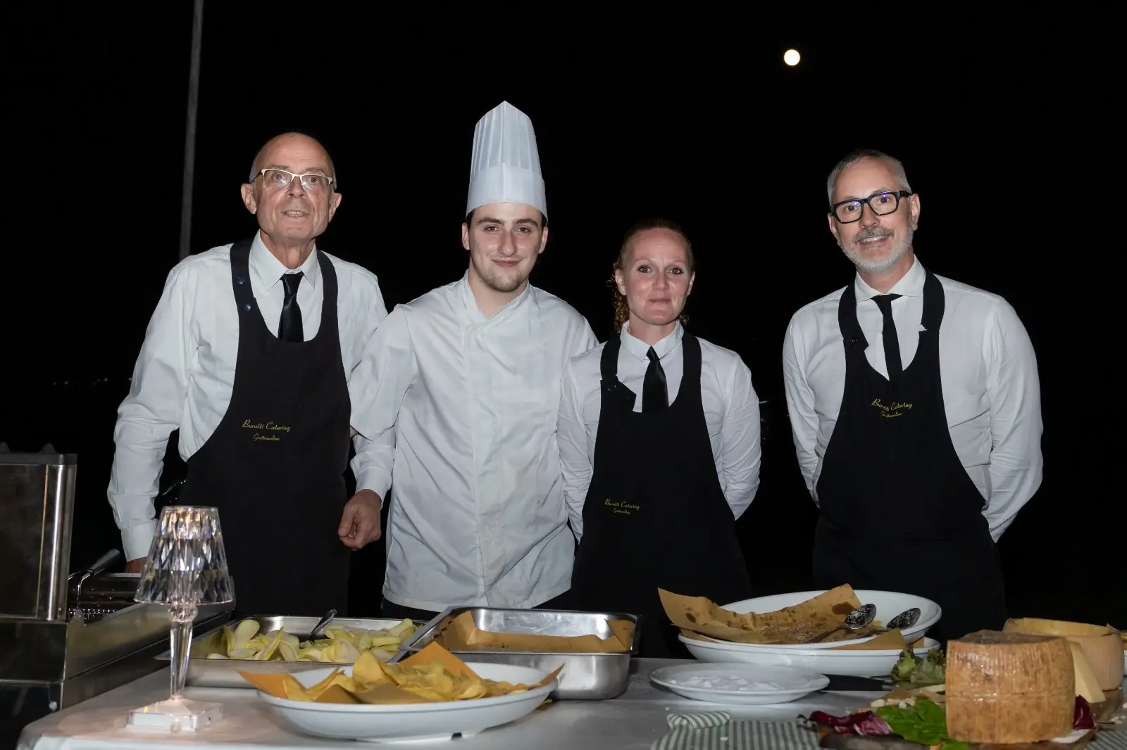Staff in attesa davanti al buffet illuminato da luci serali in giardino