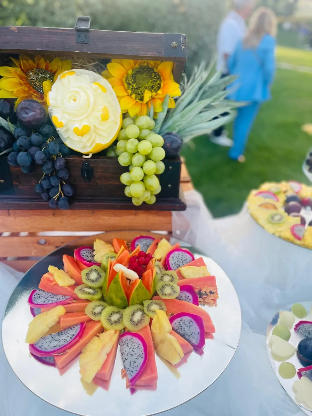 Cassetta rustica con uva agrumi e girasoli su tavolo legno per buffet stagionale