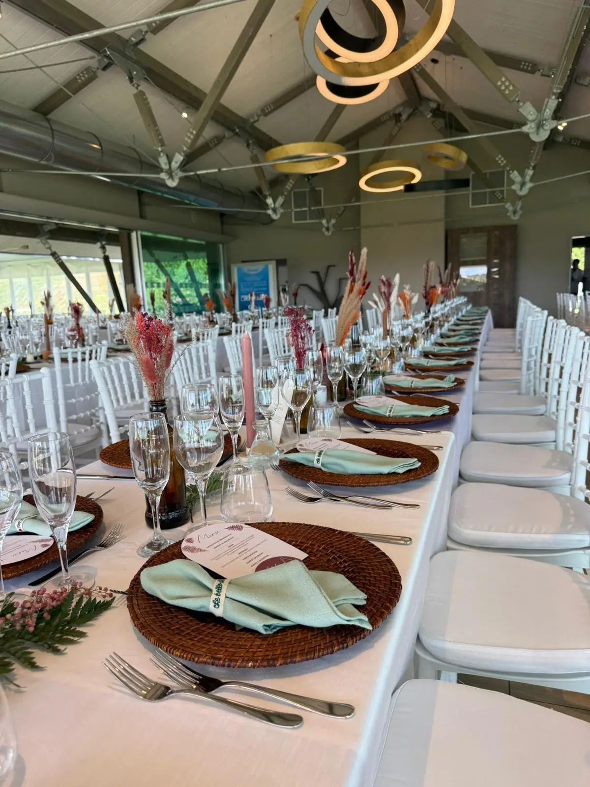 Sala interna con tavoli imperiali apparecchiati piatti rattan e luci moderne sospese