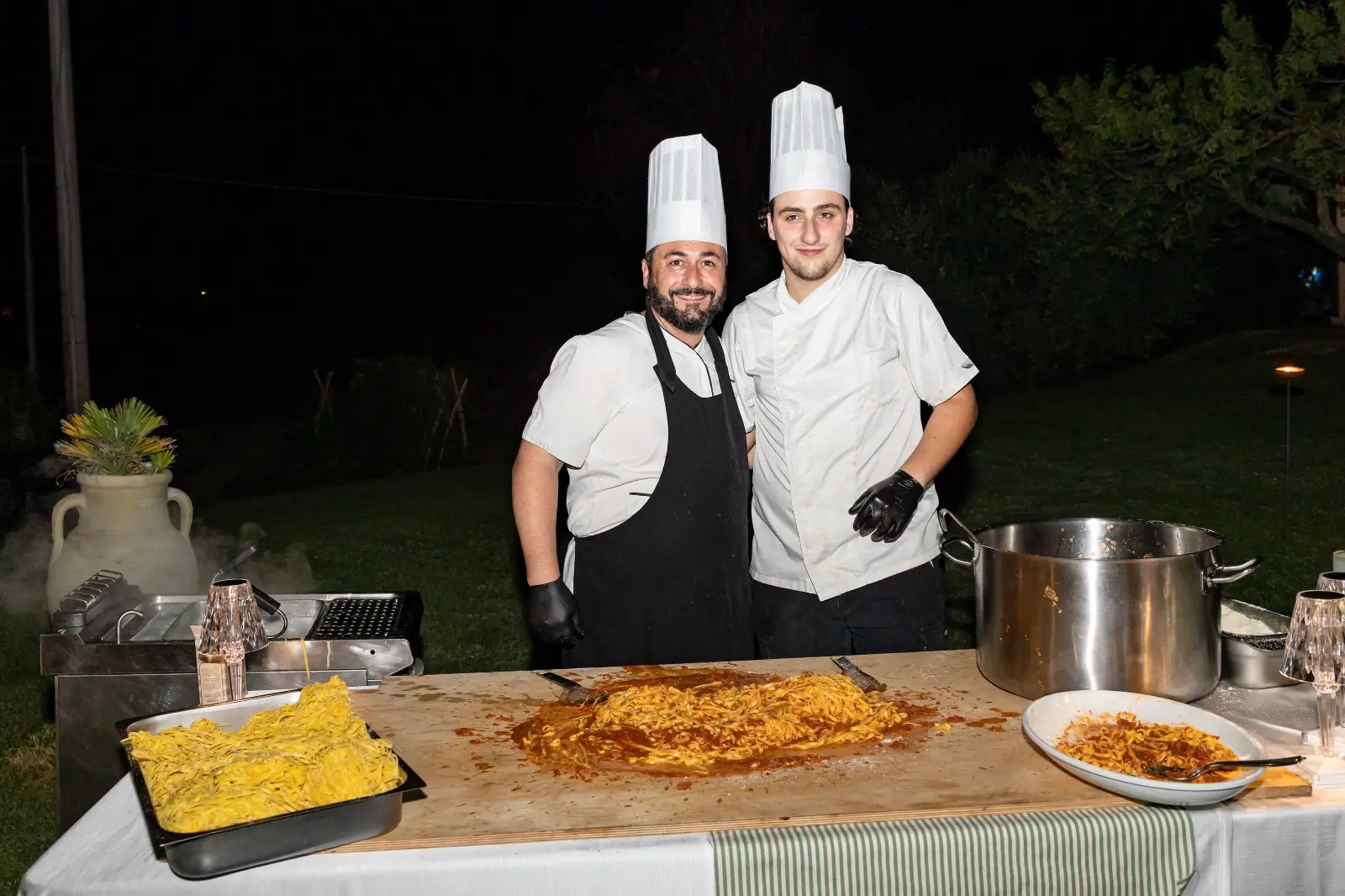 Due chef che servono tagliolini fumanti in coppia alla postazione pasta