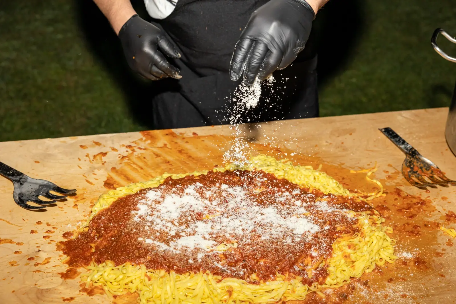 Chef che manteca tagliolini al momento davanti agli ospiti con gesto preciso