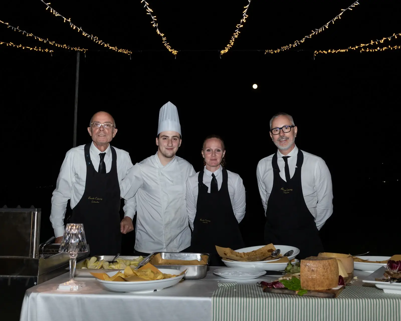 Foto notturna di gruppo staff sotto luci con sorrisi rilassati