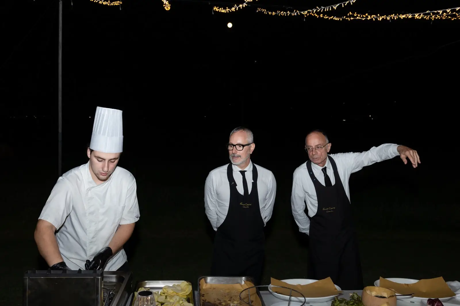 Chef e camerieri sotto luci che lavorano in sincronia durante il servizio serale