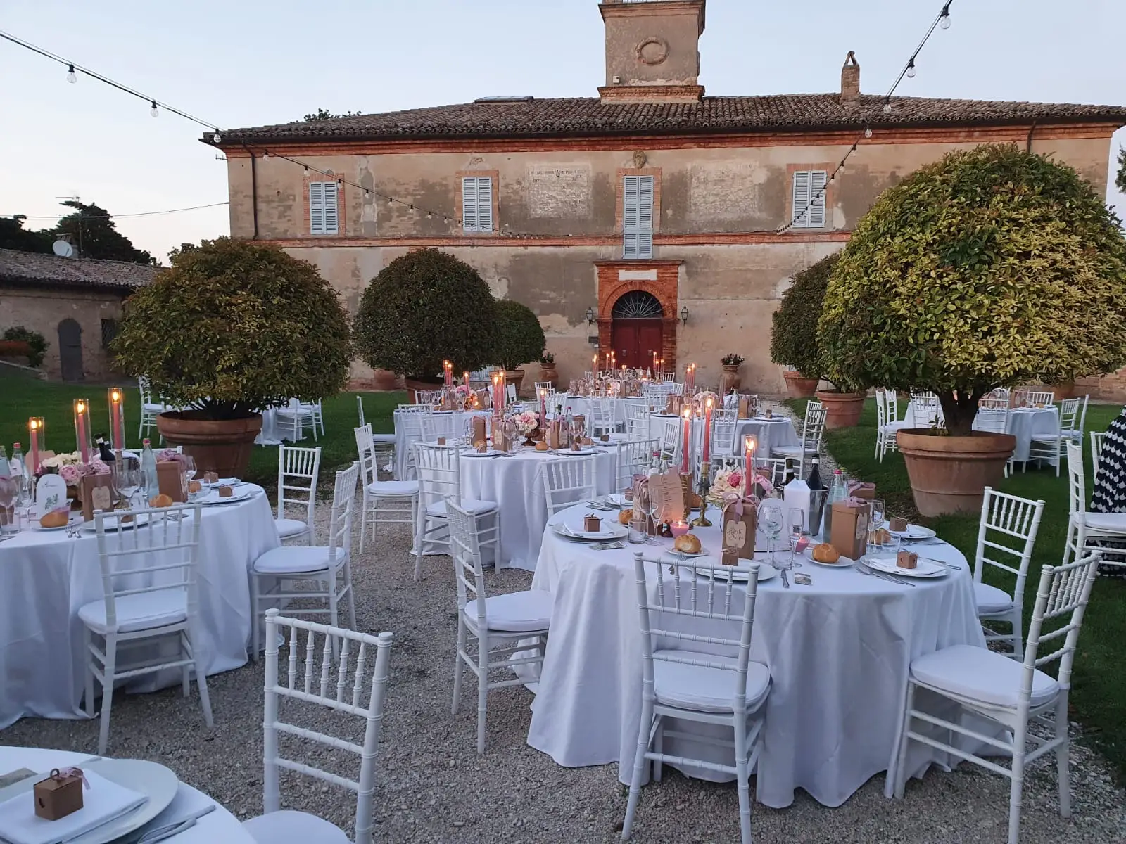 Corte all'imbrunire con tavoli total white e atmosfera gentile al crepuscolo