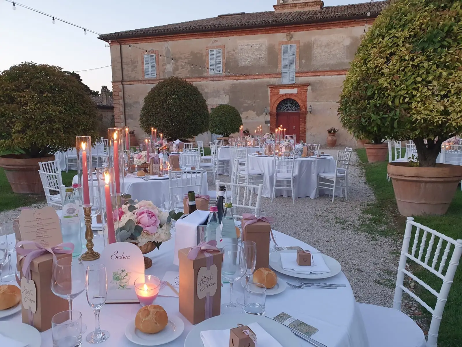 Dettaglio tavolo con candele rosa centrotavola e gift box coordinate per ospiti